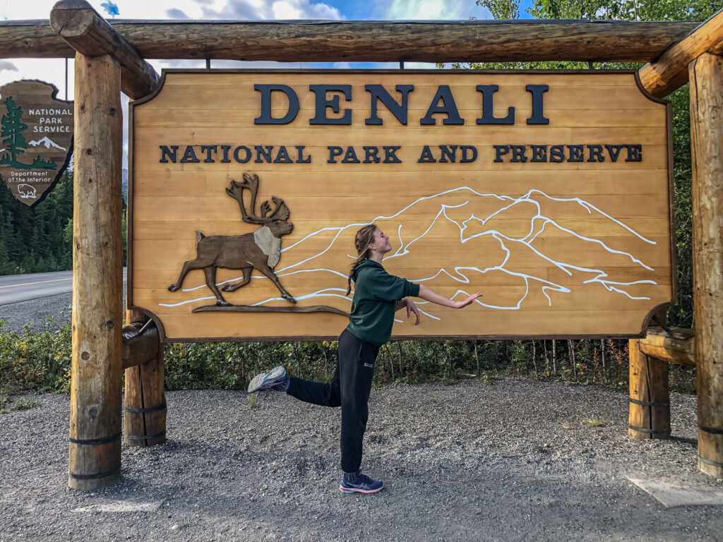 Our daughter mimics a caribou in front of the Denali National Park and Preserve entry sign.