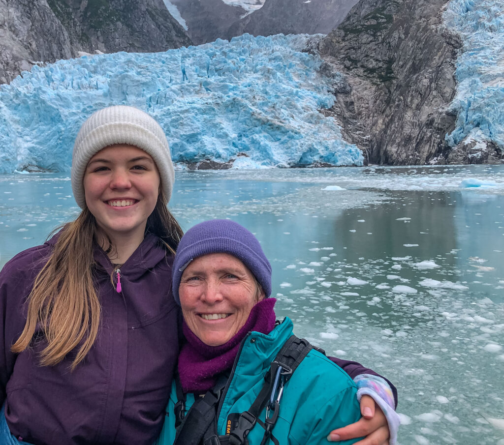 Author and teen daughter in front of the immense calving glaciers of Northwestern Fjord. 