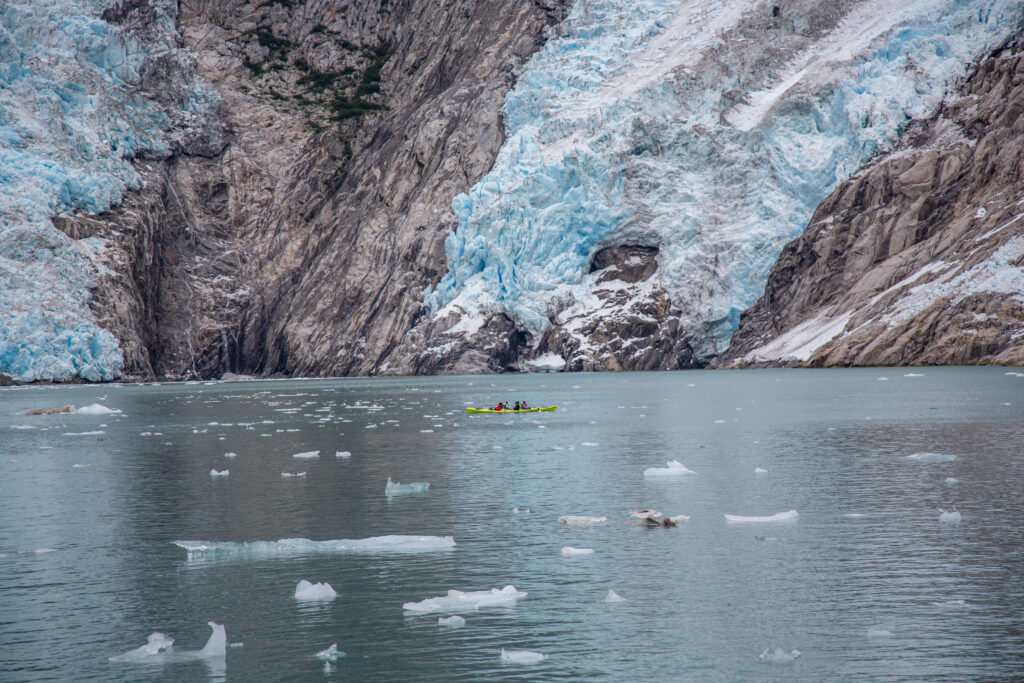 Two kayaks meander among the ice chunks, providing perspective as to just how much ice is tied up in these glaciers.
