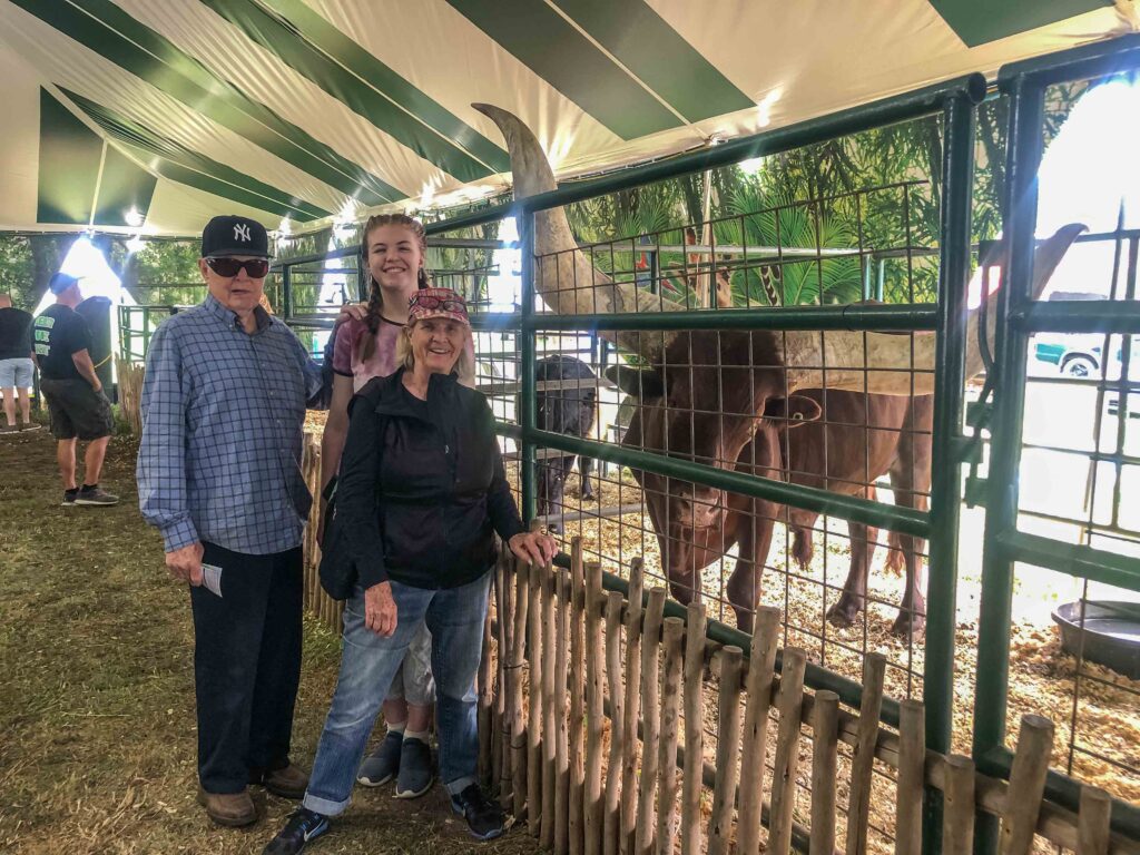 My father, daughter, and mother pose next to an African watusi, or "guy with big horns," courtesy of Eudora Farms at the NC Mountain State Fair.